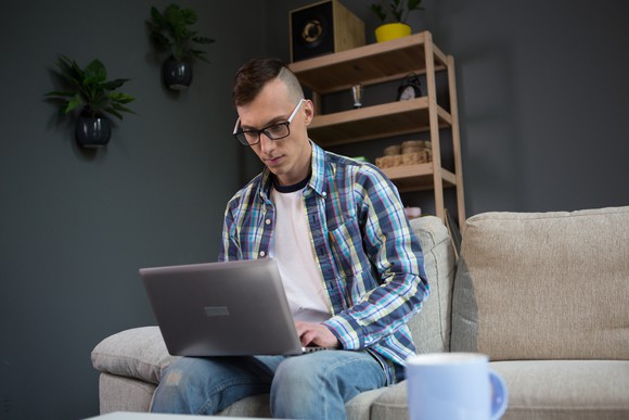 Man sitting on a couch and typing on a laptop