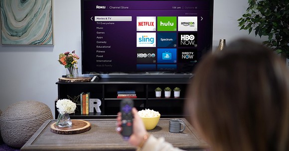 A woman using a Roku device in a living room.