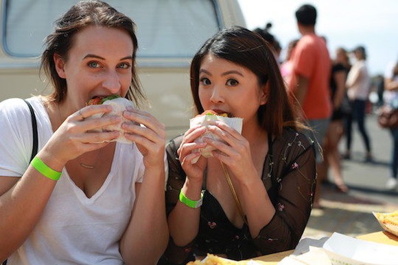 Two women eating Shake Shack burgers at an outdoor location.