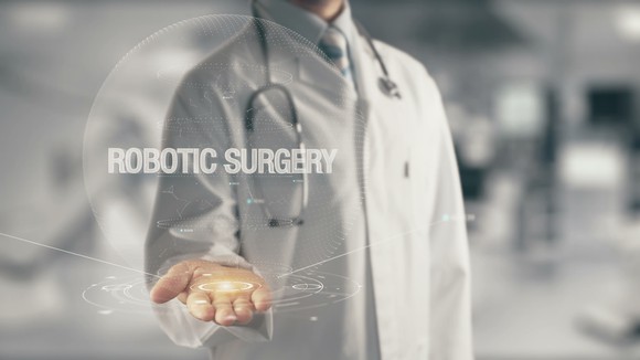 Doctor holding out hand with robotic surgery text and digital image displaying in front of him