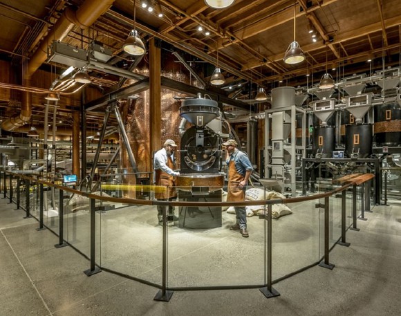 Starbucks Reserve Roastery with two workers looking at a coffee roasting machine.