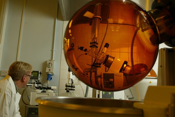 Lab tech looking at a piece of equipment inside an amber-colored glass globe.