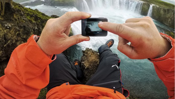 Man holding a GoPro HERO6 Black camera overlooking a waterfall