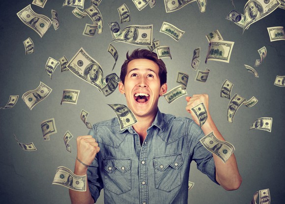 A man happily looking at dollar bills falling from above