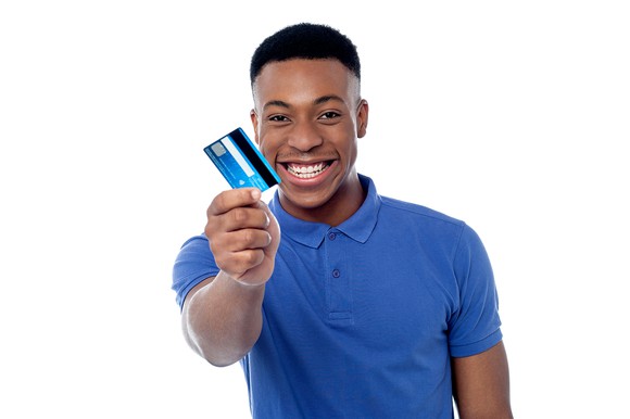 Young man smiling and holding up a credit card.