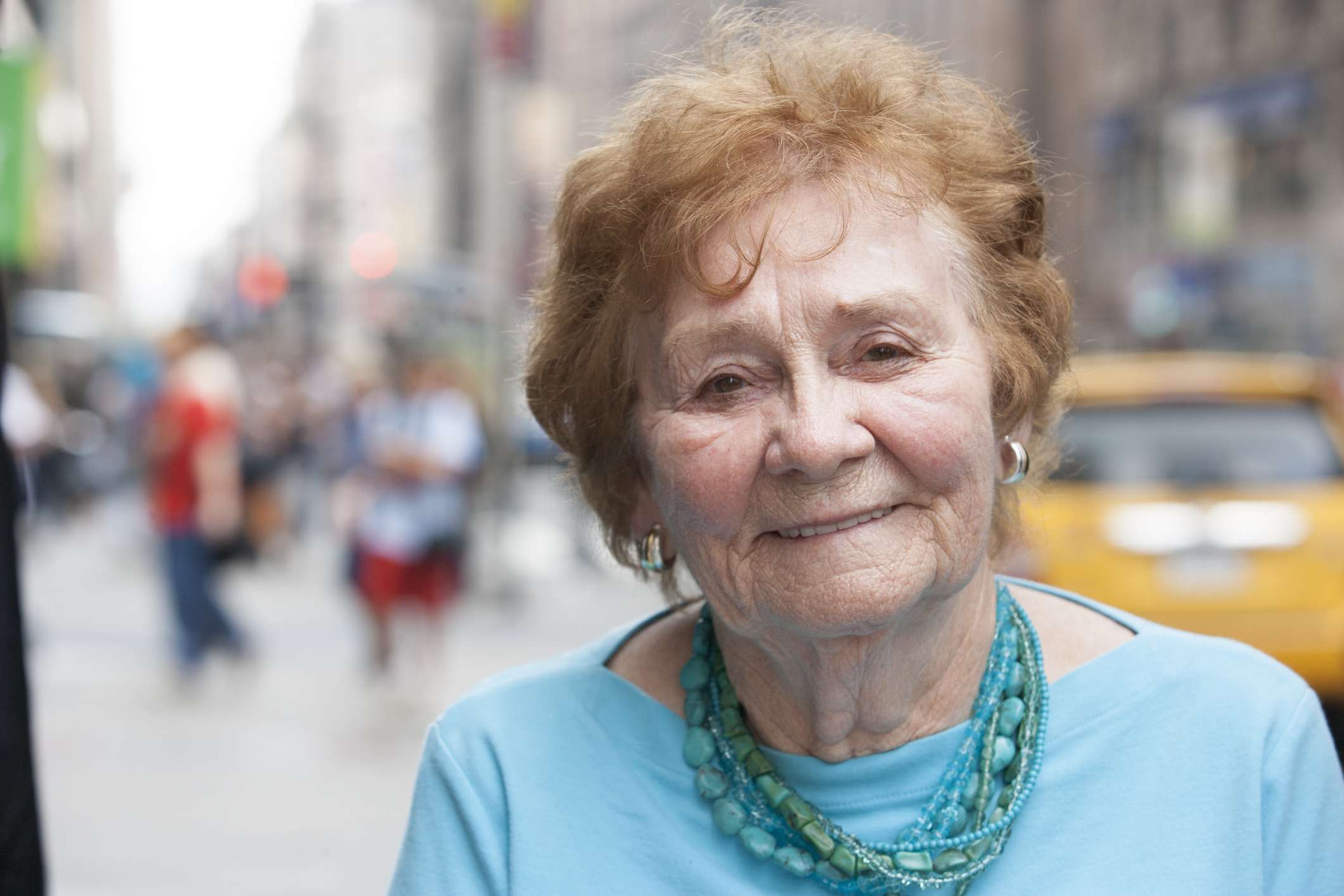 Senior woman on a city street with a taxi in the background