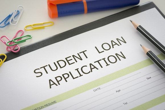 A student loan application on a desktop with pencils and paper clips.