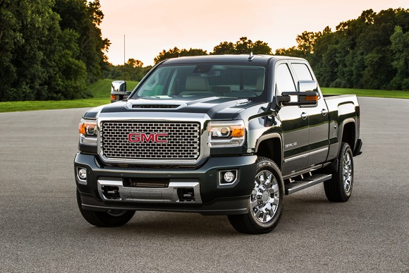 A black 2017 GMC Sierra Denali HD pickup, in a parking lot surrounded by trees.