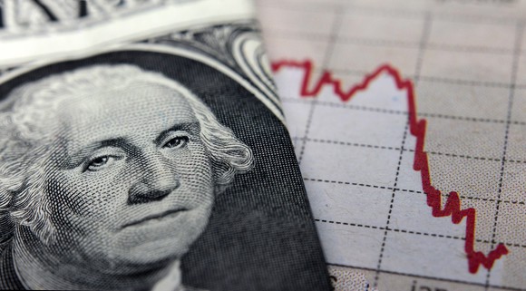 Photo of dollar bill on top of downward sloping stock chart