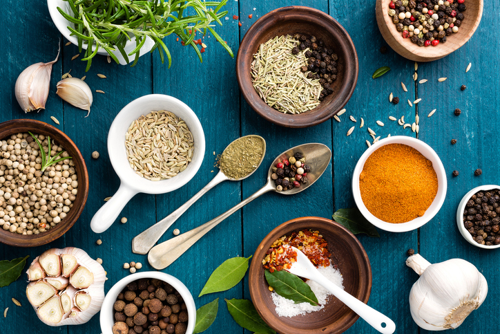 Culinary background with various colorful spices on a blue wooden table.