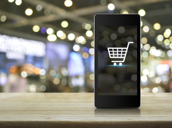 A smartphone displaying a shopping cart icon. A smartphone displaying a shopping cart icon.