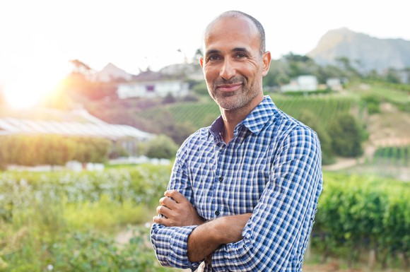 40-something man standing in a vineyard.