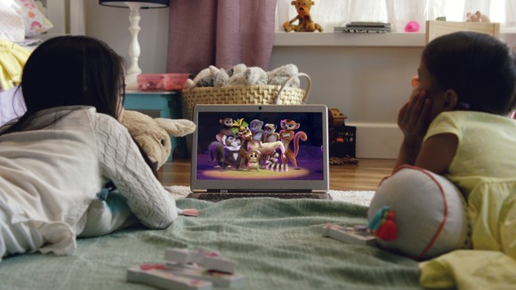Two kids watching Netflix on a computer in a bedroom.
