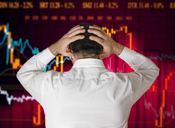 A businessman looking at a stock chart and holding his head in frustration.
