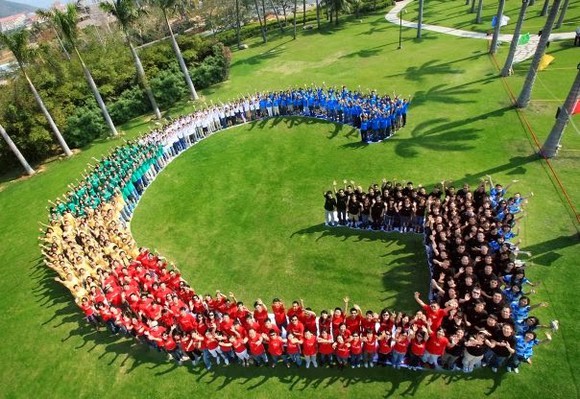 Google employees in various colored shirts arranged into Google's "G" logo.