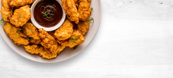 Chicken on a plate surrounding a dipping sauce.