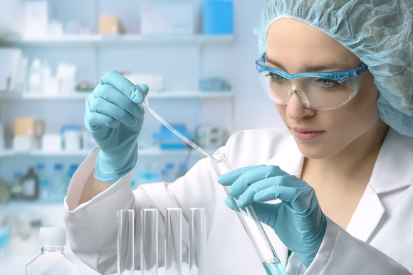 A young woman doing titration in a test tube.
