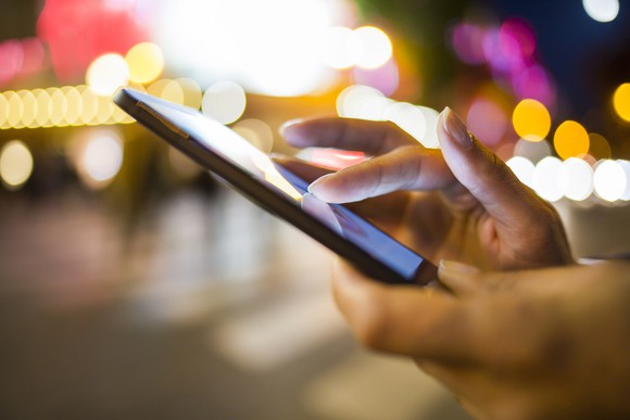 Hands using a smartphone at night.