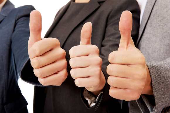 Three business people with thumbs up