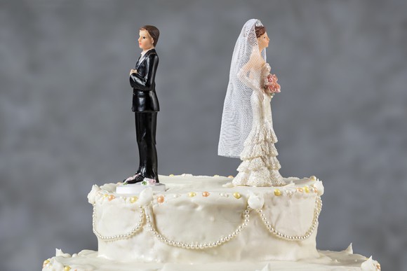 Wedding cake with figurines facing away from each other.