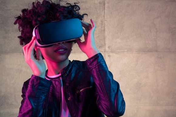 Woman with VR headset on and bright lighting in the background.