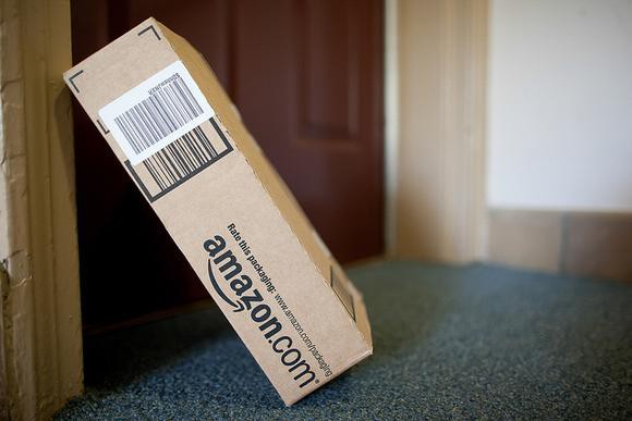 An Amazon package laid against a door for delivery.