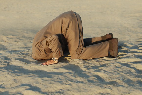 Man in suit with head in the sand