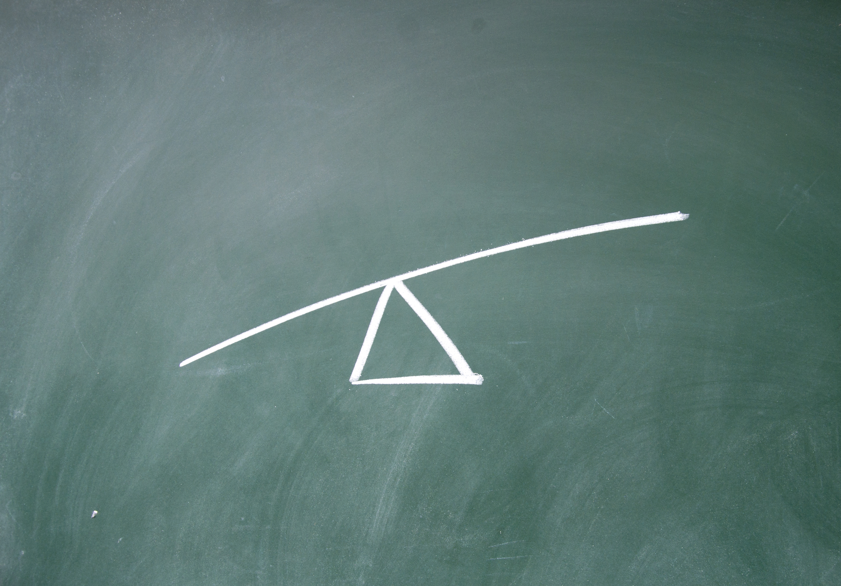 A drawing on a chalkboard of a triangle with a line balanced on top, meant to demonstrate leverage.