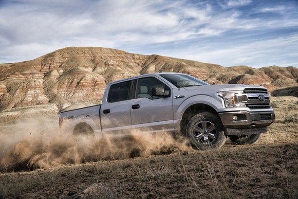 A silver 2018 Ford F-150 pickup accelerating up a sandy hill