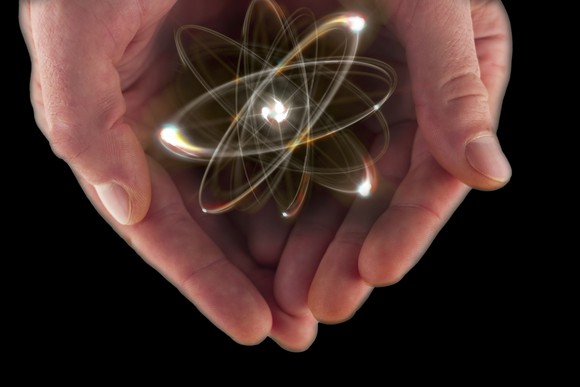 A visualization of an atom in a pair of cupped hands.