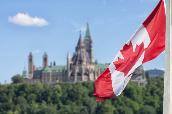 Canadian flag flying with a large building in the distance