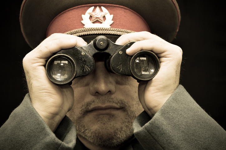 A man in Russian military uniform looking through binoculars 