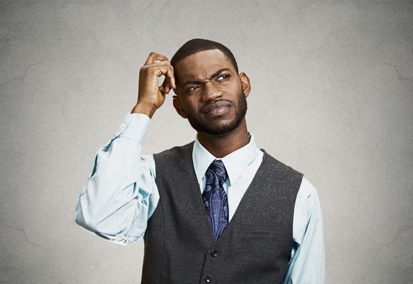 Professional man scratching his head, with a perplexed expression.