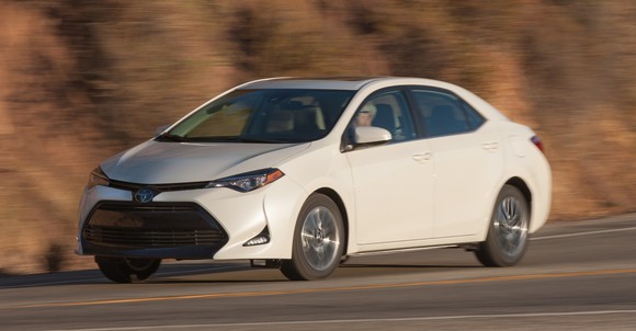 A white Toyota Corolla, a compact sedan, on a winding road.