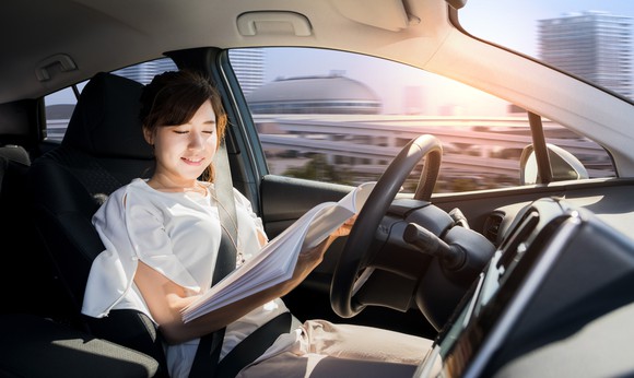 Woman reading magazine in driverless vehicle