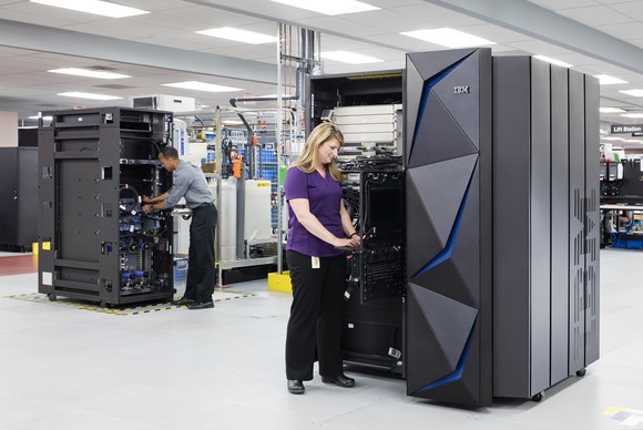 Tech staffers installing new IBM mainframes in a data center.