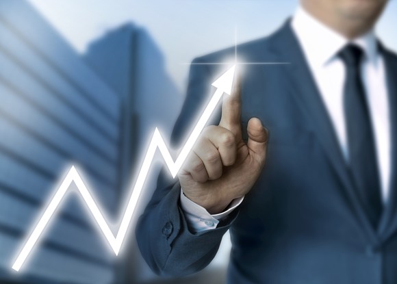 A man touching a line graph that's moving up from left to right.