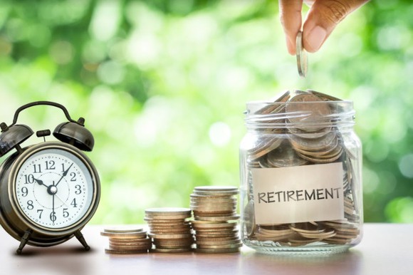Alarm clock next to jar of coins labeled retirement