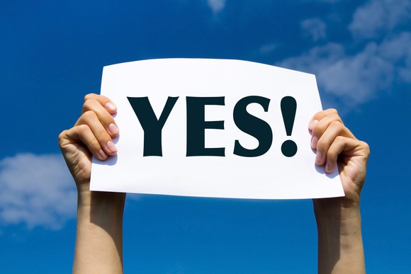 person holding up a sign that says, "YES!"