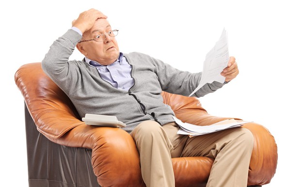 Older man looks at a bill with a surprised look on his face.