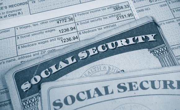 Two Social Security cards atop a pay stub.