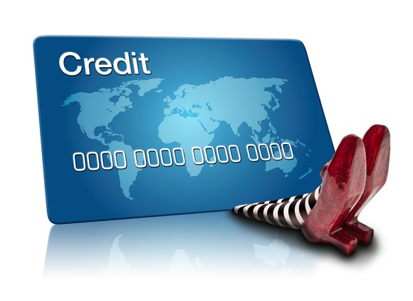 generic credit card on top of two feet wearing ruby slippers, as if the card fell on and crushed someone