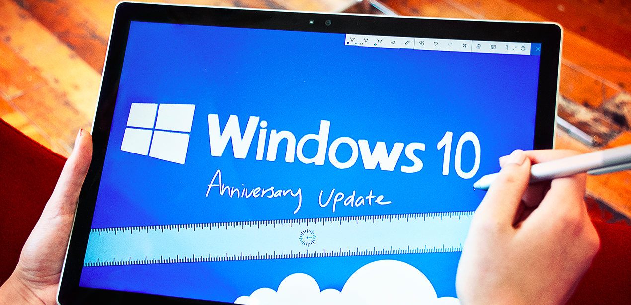The Microsoft Windows 10 logo shown above the words Anniversary Update on a  Surface Tablet 