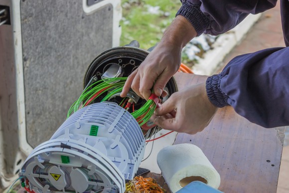 A technician working on a bundle of fiber optic network cables.