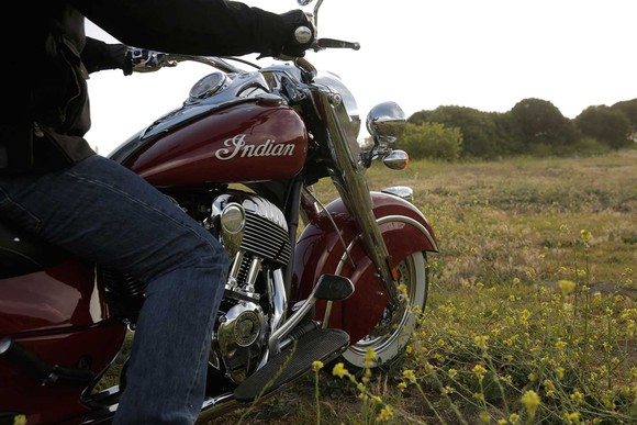 A man sitting on a Polaris Indian motorcycle that's on a field
