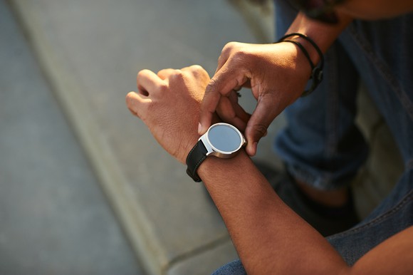 A person presses a button on a smartwatch on his left wrist.