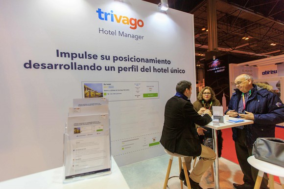 Trivago convention booth with three people at a table and a description of a company service.