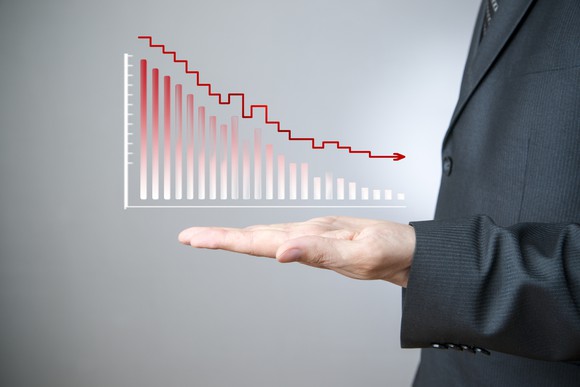 A businessman holding an upward-facing hand below a downward sloping chart