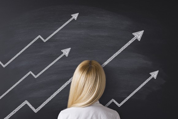 Person facing upward sloping arrows drawn on a chalkboard.