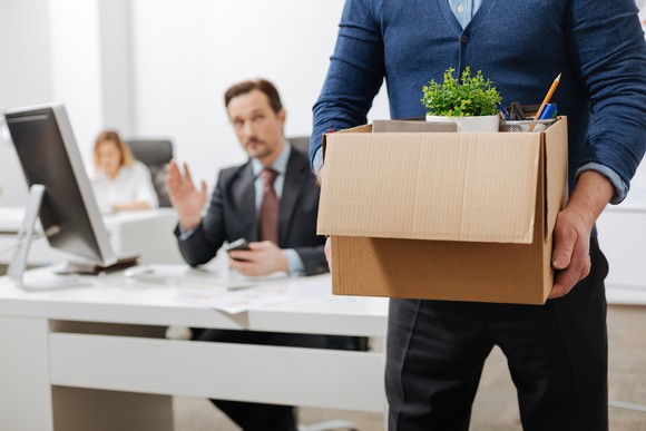 A person packing up their things at work and leaving.